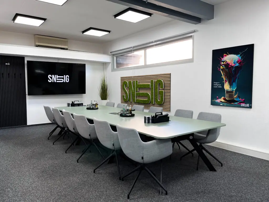 Moderne Pitch Area mit großem Konferenztisch, Markenlogo "snutig" an der Wand und kreativem Interior für professionelle Kundenpräsentationen.